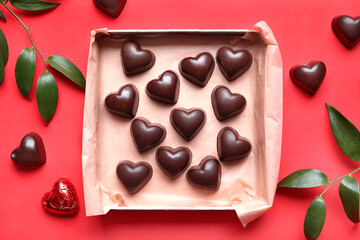 Box with tasty heart-shaped candies on red background