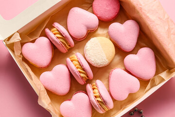 Box with tasty heart-shaped macaroons on pink background, closeup