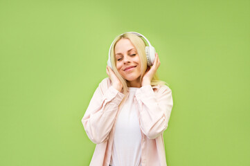Happy and relaxed young woman listening to music against green background.Relaxing and mediating.