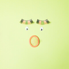 Condom nose with eyes and eyelashes on a green background. Minimal sex safe concept flat lay.