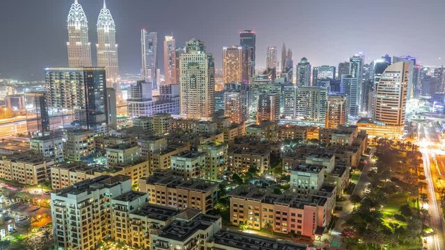 Skyscrapers in Barsha Heights district and low rise buildings in Greens district aerial night timelapse.