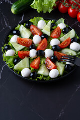 Fresh salad with cucumbers, tomatoes, black olives and feta or mozzarella cheese, with olive oil and celery