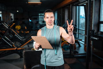 young attractive man personal trainer planning workout with clipboard in gym