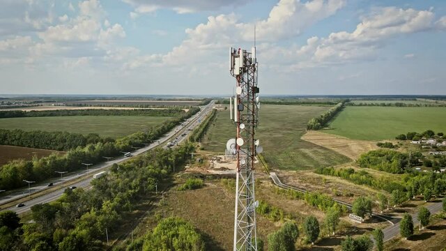Telecommunication tower 5G near highway with car traffic. Telecom tower antenna and satellite transmits the signals of cellular 5g and 4g mobile signals