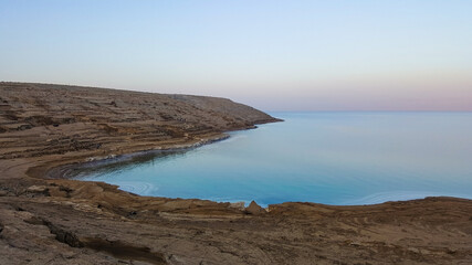 View of Dead Sea coastline. Salt crystals at sunset. Texture of Dead sea. Salty sea shore. Landscape Dead Sea coastline with natural relief channels in summer day,  failures of the soil