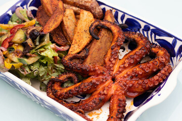 Pulpo al grill con papas gajo y ensalada sobre plato de talavera 