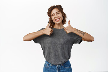 Portrait of young smiling woman showing thumbs up, good, like, approval gesture, satisfied with...