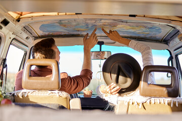 Summer travel concept. young friends or couple looking at map above to plan a camper van trip...