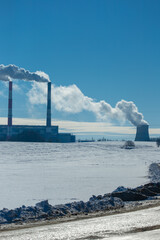 Winter landscape, snow-covered field and in the distance there are CHP chimneys on the horizon and...