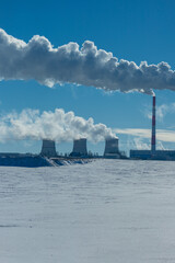 Winter landscape, snow-covered field and in the distance there are CHP chimneys on the horizon and...