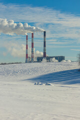 Winter landscape, snow-covered field and in the distance there are CHP chimneys on the horizon and...