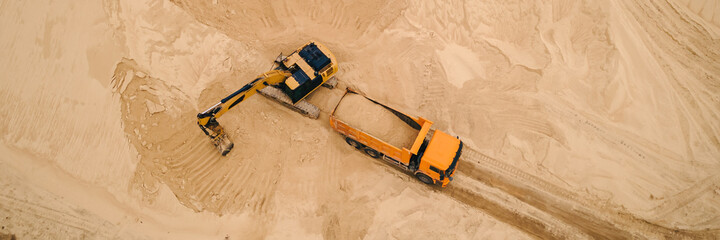 Excavator loading sand into truck in opencast sand quarry. Sand quarry, industrial extraction of...