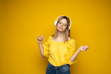 Pretty cool smiling girl in a glasses listening to music in headphones.