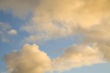 Fototapeta premium Blue sky with orange clouds illuminated by the evening sunset sun.