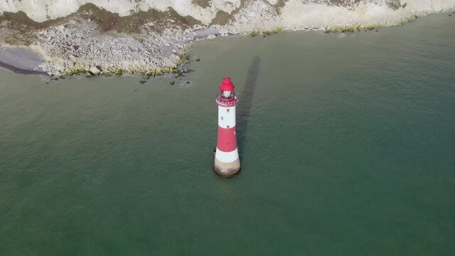 Aerial shot of Beachy Head lighthouse at abase of tall white cliff, UK