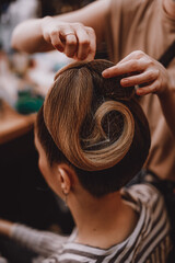 Female hands making vintage hairstyle on blond hair