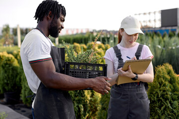 black man and woman farmers holding clipboard for checking pest and growth of plants in organic...