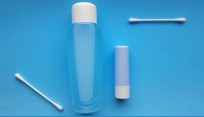 Cotton swabs, cotton pad, makeup remover, hygienic lipstick on a blue background.