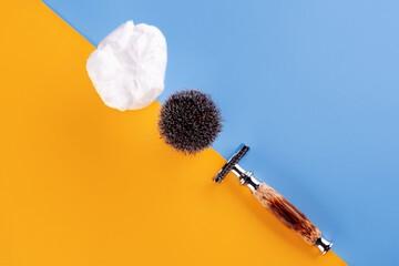 Razor,  brush and foam contrasting yellow and blue background. View from above. Space for text. 