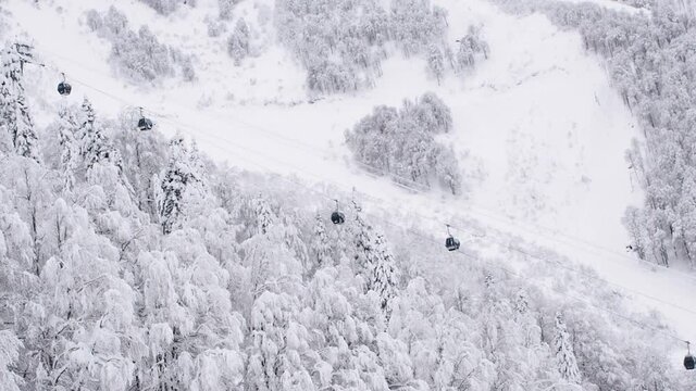 Mountain winter landscape Cable car movement. Over the mountains, forest, slope. Ski resort. Trees in the snow.