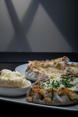 Traditional Finnish foods - Fresh Karelian pies with rice pudding filling and egg butter and chives topping against black background. - obrazy, fototapety, plakaty