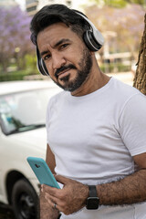 portrait of latin man with headphones in the city looking at camera