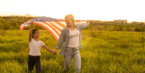 happy mother and daughter with american flag outside