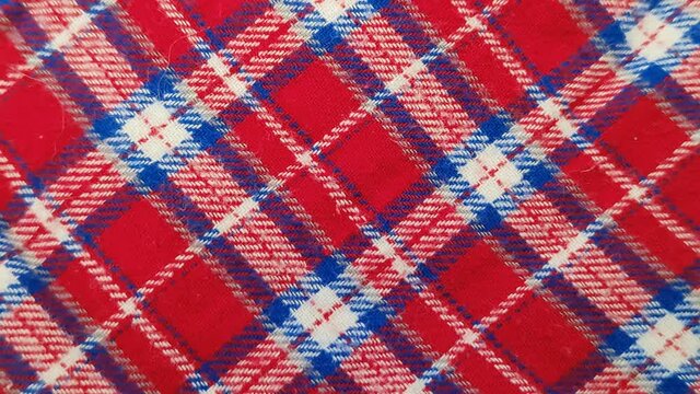 Flannel fabric with a checkered pattern. Scottish plaid red and blue fabric. Macro photography of soft woolen fabric. Rotation, close-up.