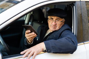 serious businessman driving his car and looking at smartphone