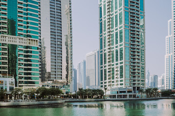 Fototapeta na wymiar Modern city skyscrapers buildings at sunset time with business and residential towers around the lake and palm trees