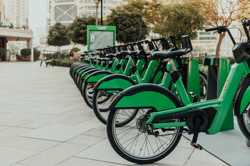 Green eco-friendly bike public rentals in a row located outside in a park area