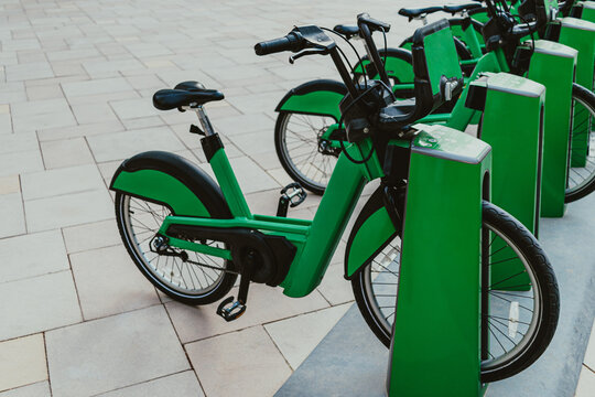 Green eco-friendly bike public rentals in a row located outside in a park area