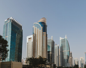 Modern city skyscrapers buildings at sunset time with business and residential towers around the lake and palm trees