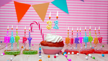 Thirty-one year happy birthday card on a pink background, with a number in a cupcake. Beautiful happy birthday background with number 31 with burning candle. Festive background with colorful decoratio