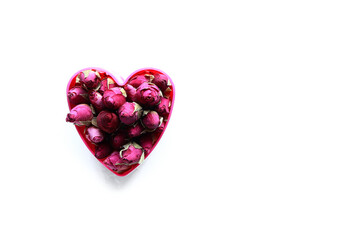 Dried roses buds in heart shaped bowl on white background with a place for text or images. valentine day or mother's day concept