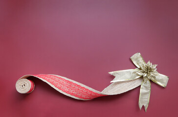 Burlap ribbon and gold bow glittering on dark pink background. Christmastime celebration. Space for text.