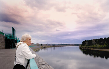 Fototapeta premium Day dreaming senior woman outdoors. Contented senior woman looking thoughtful during walking countryside