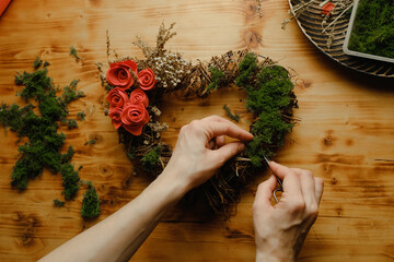 Female hands makes floral wreath. Spring home decoration with dried twigs, moss and diy flowers....