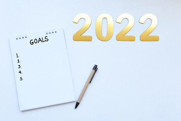 2022 golden number with goals on blank notebook and pencil on desk. copy space for text. New year goals 2022 concept.