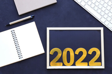 2022 number on blank chalkboard with notebook, pencil and keyboard on the table.copy space for text.New year goals 2022 concept.