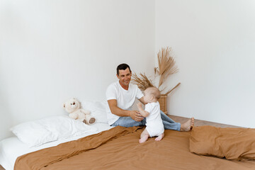 dad plays with the baby on the bed