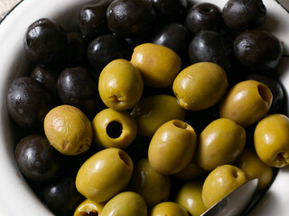 Green and black olives in a plate closeup