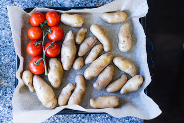 fresh sweet potatoes and tomatoes on a pan