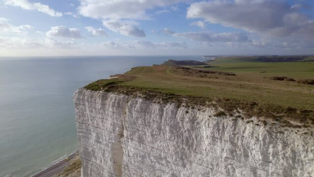 Reversing aerial shot away from Beachy Head cliff and coastline revealing lighthouse