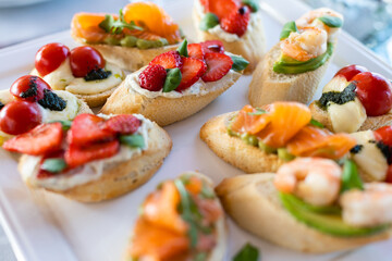 Bruschetta with tomatoes, mozzarella cheese and basil on a cutting board. Traditional italian appetizer or snack, antipasto. Caprese salad bruschetta. Top view with copy space.
