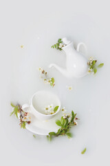 White teapot and tea cups with cherry flowers , leaves