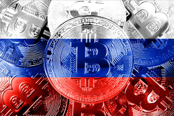 Holds a physical version of Bitcoin and the Russian flag. Conceptual image of cryptocurrencies and...
