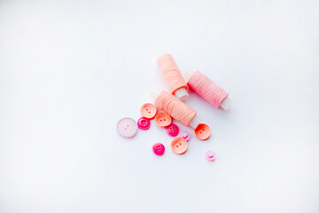 Pink threads and pink buttons on a white background. Sewing themes.