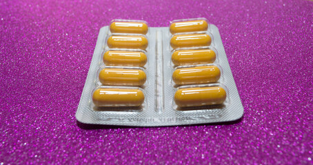 yellow capsules pills pills in a silver blister on a crimson background close-up