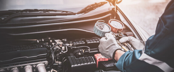 Close up hand of auto mechanic using measuring manifold gauge check the refrigerant and filling car...